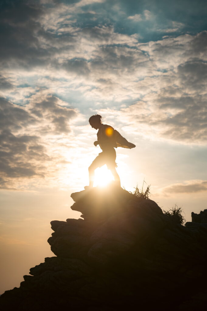 Nicolas Loewer standing on a rock in the light of sunrise, symbolizing alignment, new beginnings, and embodied clarity