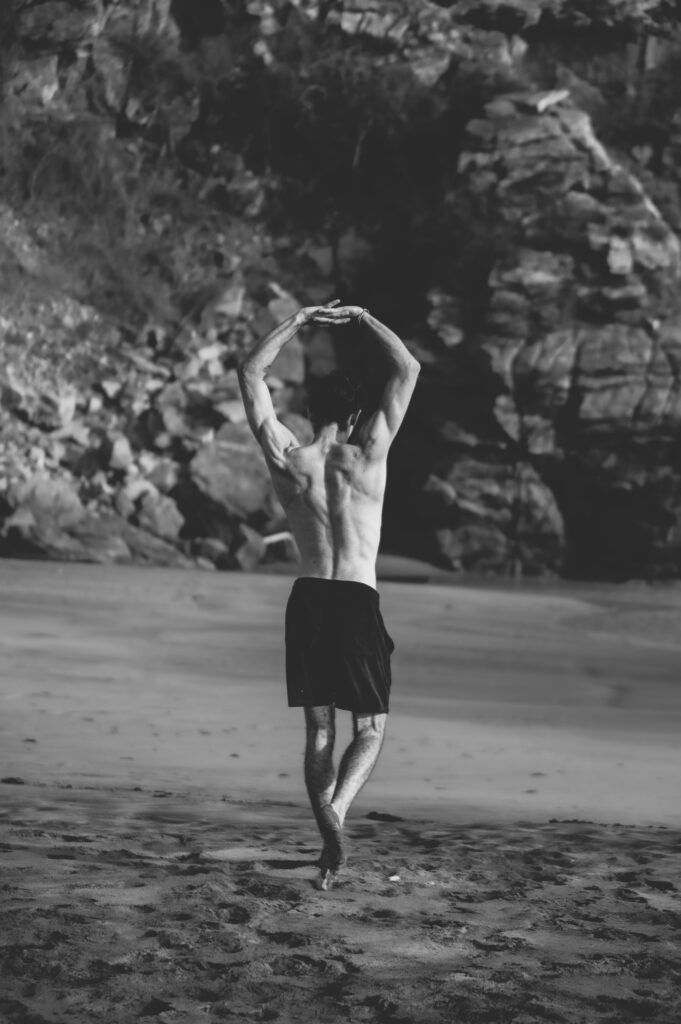 Nico Loewer am Strand in Schwarz-Weiß, mit erhobenen Händen in Bewegung auf dem weg zu einer Live Coaching Session