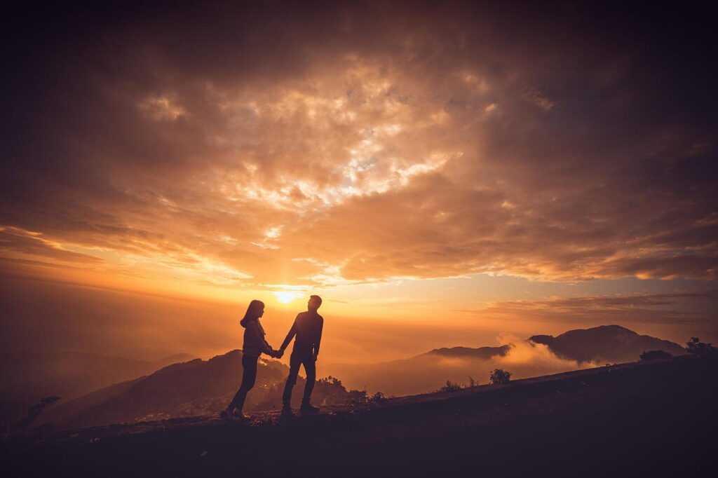 Couple hiking up a mountain together at sunrise