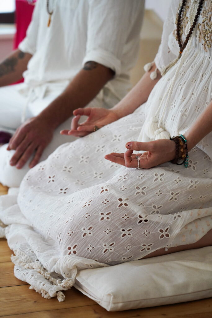 Participants in a meditation posture with Om Mudra during a Tantra workshop, focusing on presence and embodied awareness