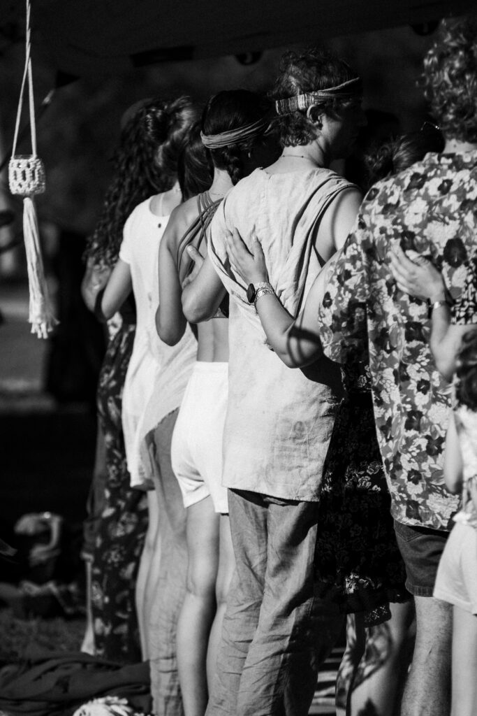 Hand placed at heart level of a participant during a black-and-white Tantra workshop, symbolizing closeness, presence, and deep connection