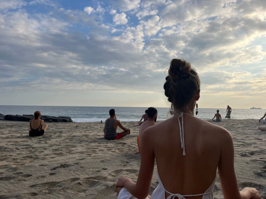 Tantrische Übung am Strand mit Fokus auf Verbindung zu den Elementen während eines Workshops